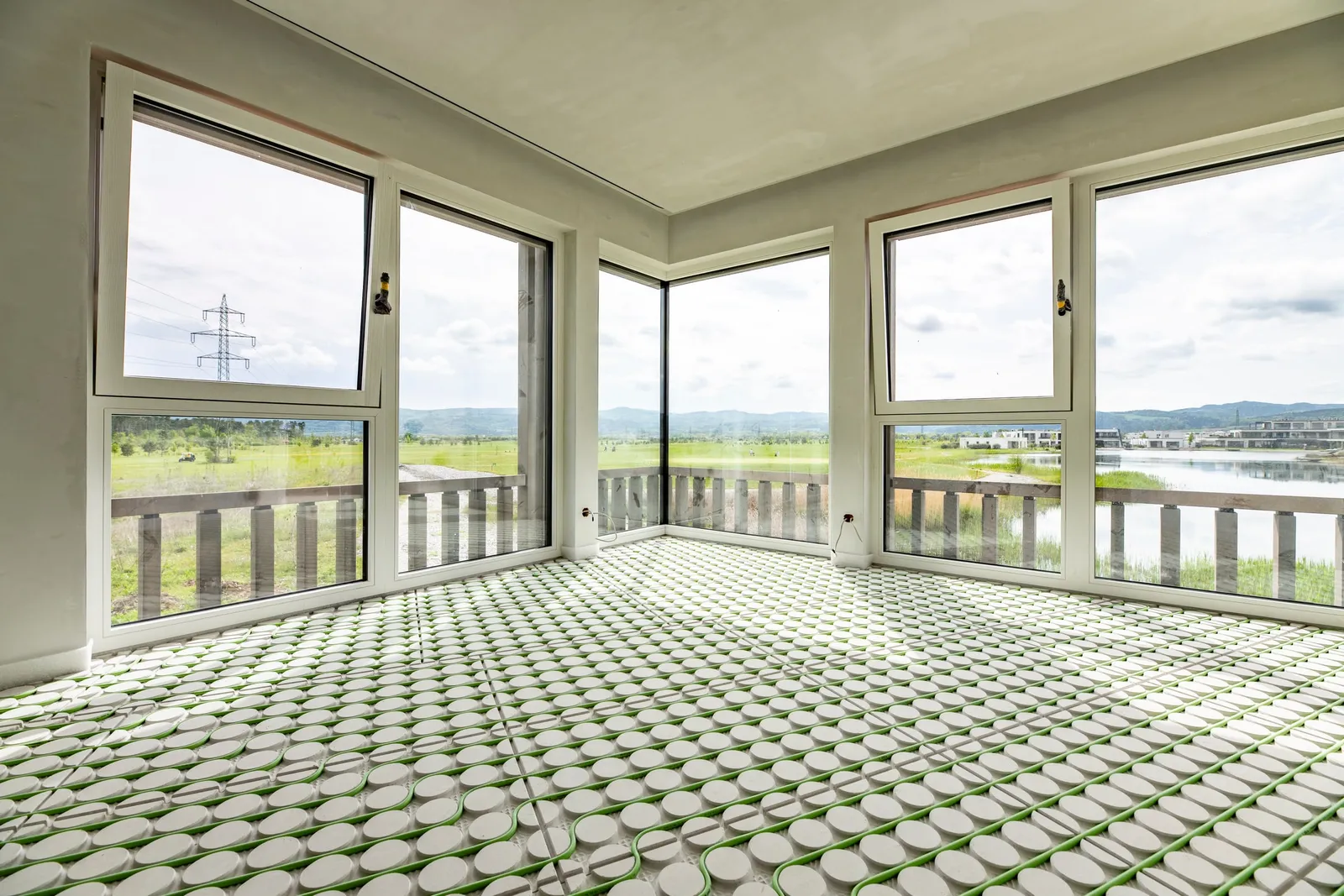 Raum mit verlegten Fußbodenheizungsplatten und grünen Heizrohren, Blick auf den See