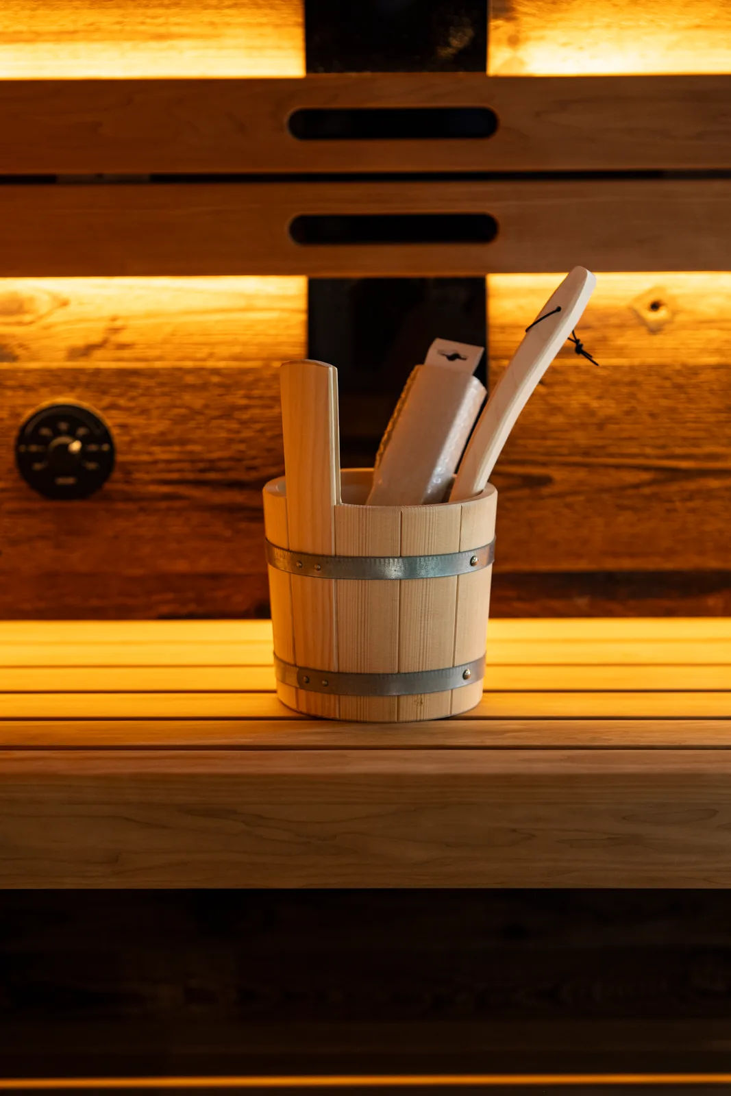 Saunakübel aus Holz auf der beleuchteten Bank der Saunabox Altholz